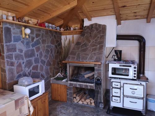 a kitchen with a stone fireplace in a house at Къща за гости Григорови in Raduil