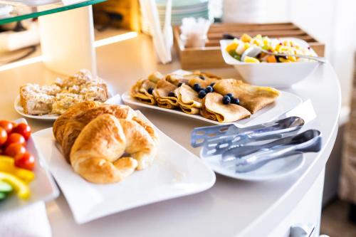 a table topped with plates of pastries and bowls of fruit at Hotel MAGISTR Vsetín in Vsetín