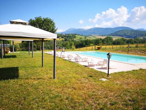 a swimming pool with a white umbrella and chairs next to it at Da Foschetta in Matelica