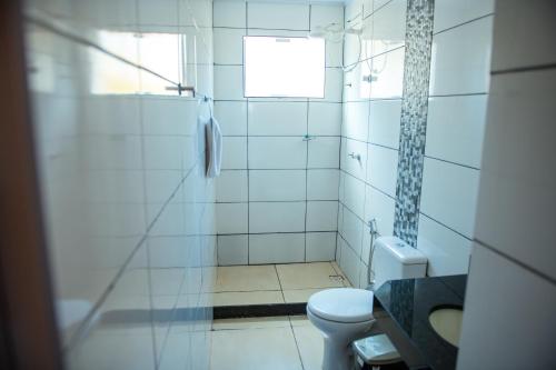 a white bathroom with a toilet and a shower at Pousada Solar Dona Dora in Capitólio