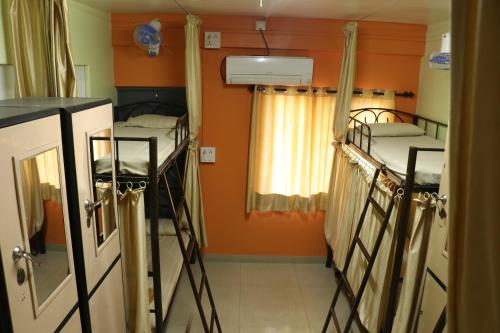 2 łóżka piętrowe w pokoju z pomarańczowymi ścianami w obiekcie Ashirwad Guest House (Male Only) w mieście Pune