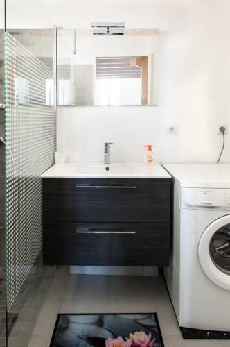 une salle de bain avec un lavabo et une machine à laver dans l'établissement Les Beaux Rivages - Superbe T1 bis de 35 m2 - stationnement gratuit - proche gare et port - Apt Gauche, à La Rochelle