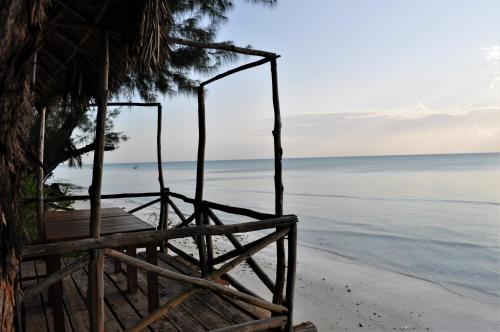 a bench on the beach next to the ocean at Seasons Lodge Zanzibar in Pongwe