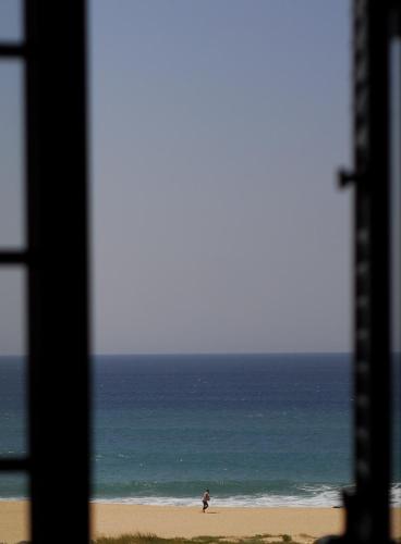 a person standing on a beach near the ocean at Supertubos Beach Hostel in Peniche