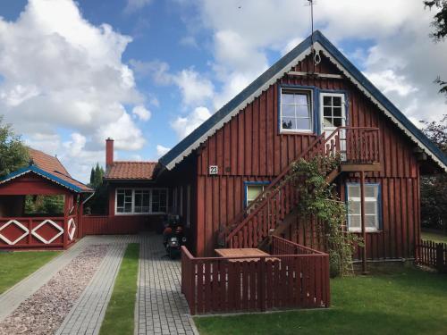 a red house with a staircase in front of it at Private apartments in Preila in Preila