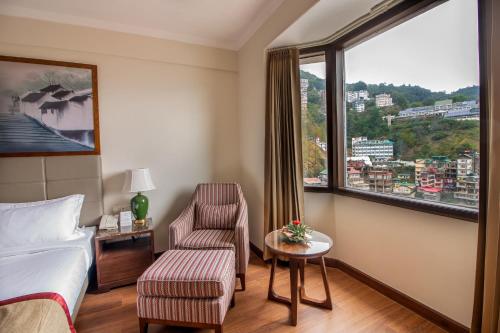 a hotel room with a bed and a chair and a window at 8fold by LaRiSa in Shimla