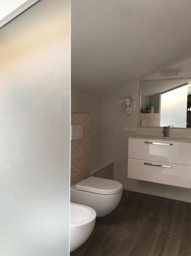 a bathroom with a toilet and a sink and a mirror at B&B "al Pesce Vela" in Albese Con Cassano