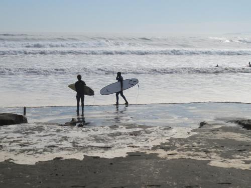 two people walking on the beach with their surfboards at Hotel Trocadero in Concón