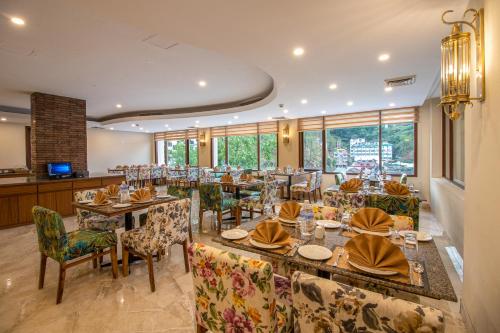 a dining room with tables and chairs and windows at Larisa Shimla in Shimla