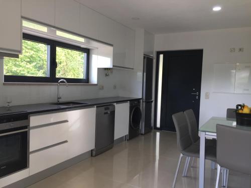 a kitchen with white appliances and a table and chairs at Quinta do Couto (alojamento local) in Celorico de Basto