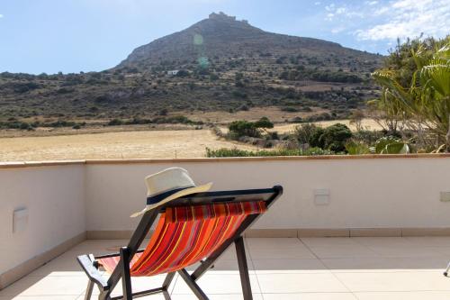 a hat sitting on a chair on a balcony with a mountain at Il Borgo Del Principino in Favignana