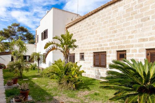 a brick building with palm trees in the yard at Il Borgo Del Principino in Favignana