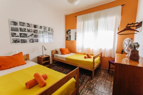 a bedroom with two beds and a chair and a window at Olive Hostel Lagos in Lagos