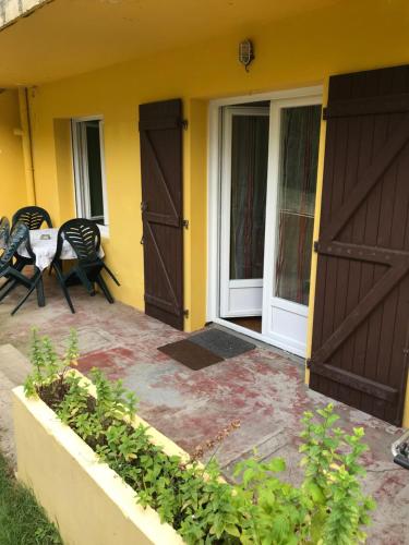 une maison avec deux portes, une table et des chaises dans l'établissement Au calme près de la forêt à 2 kms des plages, à Capbreton