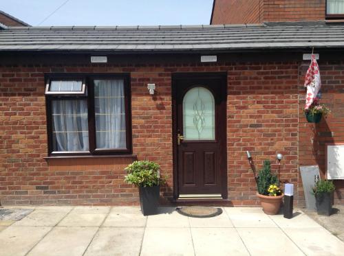 a brick house with a brown door and windows at The Anfield Apartment in Liverpool