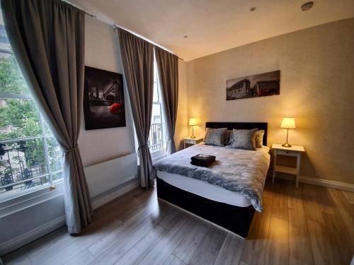 um quarto com uma cama e uma grande janela em Victoria Lodgings London em Londres