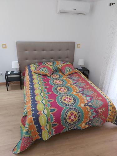a bed with a colorful blanket on top of it at Tipico Romântico II in Setúbal