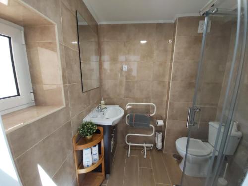 uma casa de banho com um lavatório, um chuveiro e um WC. em Tipico Romântico II em Setúbal