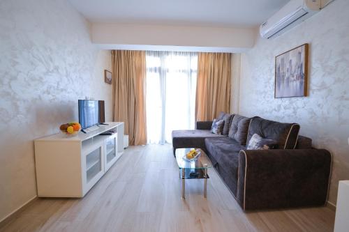a living room with a couch and a television at Brand New Apartments - free parking in Sveti Stefan