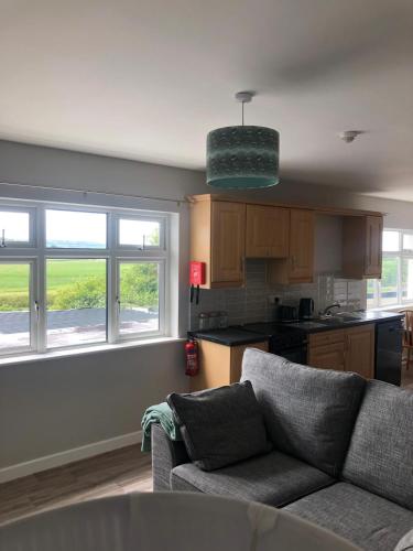 a living room with a couch and a kitchen with windows at Castle View in Listowel