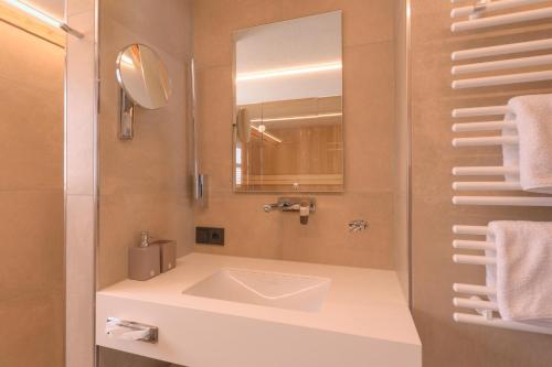 a bathroom with a sink and a mirror at ArlBerglife Ferienresort in Pettneu am Arlberg