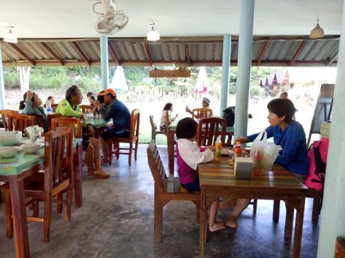 a group of people sitting at tables in a restaurant at TA YAI HOMESTAY (ตา ยาย โฮมสเตย์) in Ko Kood