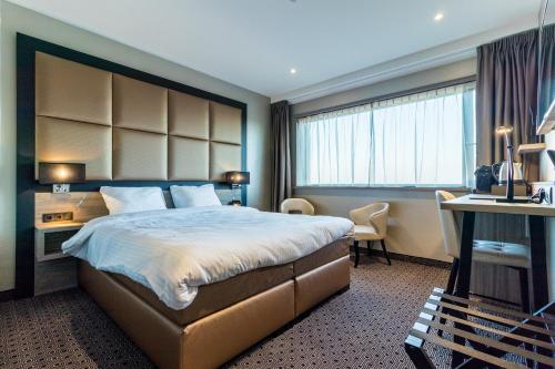 a hotel room with a large bed and a desk at Riva hotel Den Haag - Delft in The Hague