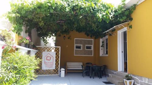 a yellow house with a table and chairs on a patio at Hostel das Flores in Senhora da Hora