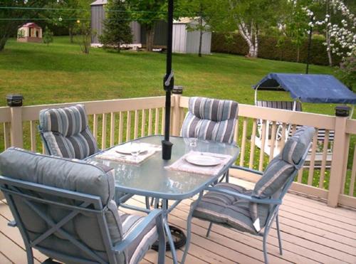 una mesa y sillas en una terraza con sombrilla en Gîte Au p'tit bonheur B&B en Coaticook