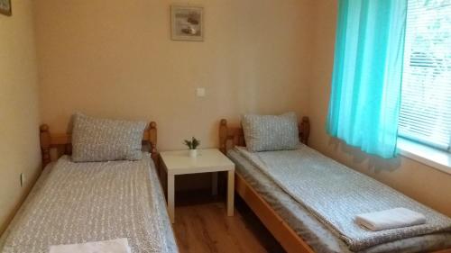 two beds in a room with a table and a window at Къща за гости DANI DREAM in Sapareva Banya