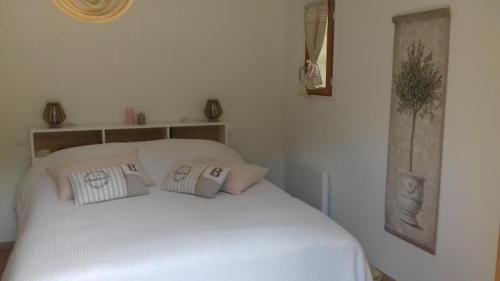 ein Schlafzimmer mit einem weißen Bett mit Kissen darauf in der Unterkunft à l'orée du bois in Bois-Jérôme-Saint-Ouen