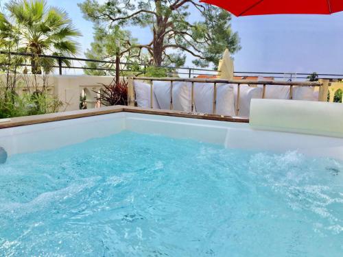 une grande piscine avec un parasol rouge dans l'établissement Villa centre ville proche plage, à Nice