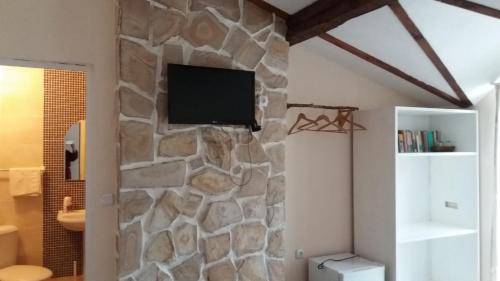 a room with a stone wall with a tv on it at Къща за гости DANI DREAM in Sapareva Banya