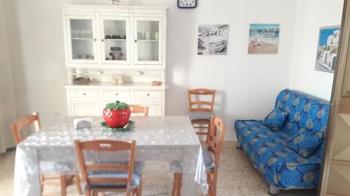 une salle à manger avec une table et un canapé bleu dans l'établissement Villetta Li Giannelli, à Marina di Mancaversa