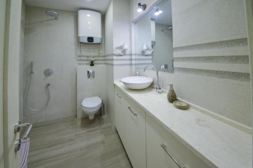 a white bathroom with a sink and a toilet at Brand New Apartments - free parking in Sveti Stefan