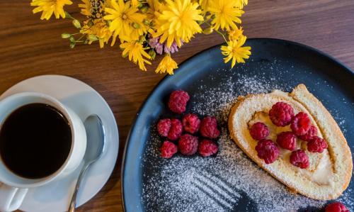 a blue plate with a toast with raspberries and a cup of coffee at Travel Inn Kazbegi in Stepantsminda