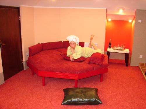 Una mujer yace en un sofá rojo en HOTEL VILA MITIC LUXX SPA centar, en Leskovac
