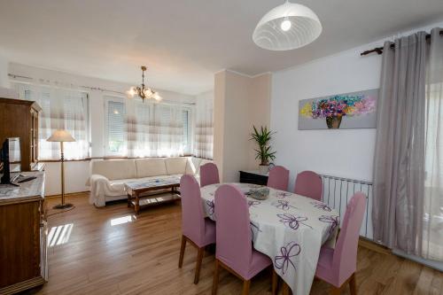 a dining room with a table and purple chairs at Apartmani Rab in Kampor