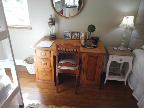 escritorio de madera con silla y espejo en Happy Lands Farmstay, en Addo