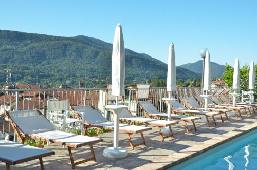 - une rangée de chaises longues à côté de la piscine dans l'établissement Hotel Ristorante Stampa, à Lavena Ponte Tresa
