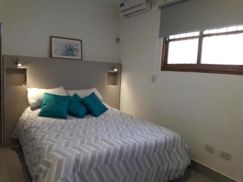 een slaapkamer met een bed met blauwe kussens en een raam bij Apart Camilo in Mendoza