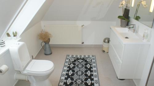 a white bathroom with a toilet and a sink at Billesgade Rooms in Odense