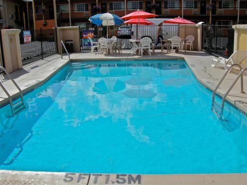 a large blue swimming pool with chairs and umbrellas at Americas Best Value Inn - Pendleton in Pendleton