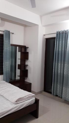 a bedroom with a bed and a window at Sufia House Apartment in Dhaka