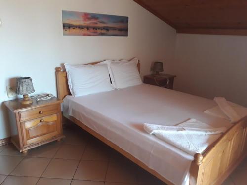 a bedroom with a large white bed and a night stand at Dom Shtakovi in Pomorie