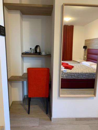 a bedroom with a red chair and a mirror at Villa Cuore in Tavernerio