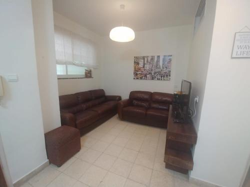 a living room with brown leather couches and a table at Lovely apartment premium location in Ramat Gan