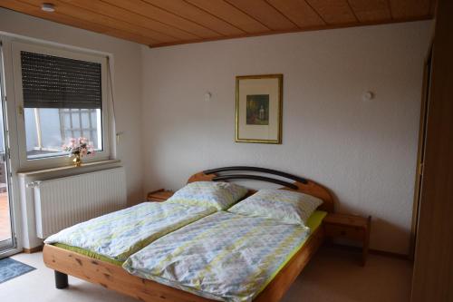 1 dormitorio con 1 cama con cabecero de madera y ventana en Ferienwohnung Donauidylle en Lauingen