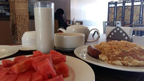 een tafel met een bord watermeloen en pasta en melk bij Cityview Hotel Fort Portal in Fort Portal