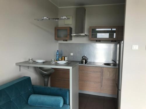 a small kitchen with a counter and a blue chair at Dworzec Gdański Apartament in Warsaw
